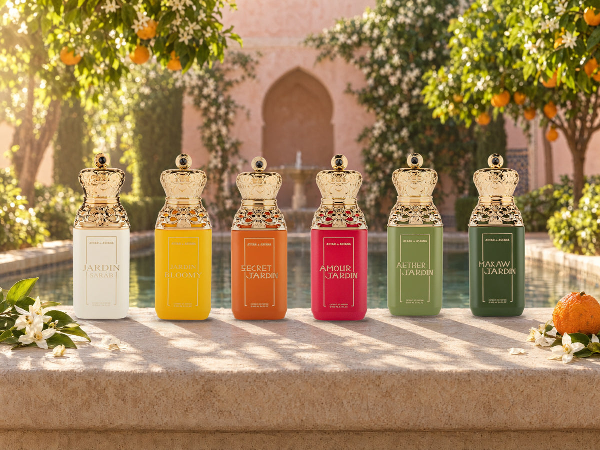 The six Jardin bottles, Sarab, Bloomy, Secret, Amour, Aether and Makaw, standing in a row on the limestone rim of a pool in a walled garden, orange trees and jasmine behind them in morning sun
