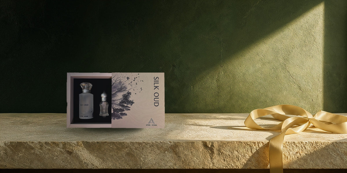 The Silk Oud set open on a limestone ledge against a deep green wall, with a gold silk ribbon tied beside it